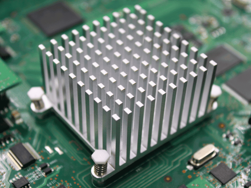 Silver aluminum pin-fin heat sink mounted on a green PCB.