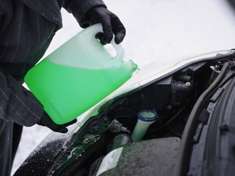 Maintenance technician performing a coolant flush on a vehicle