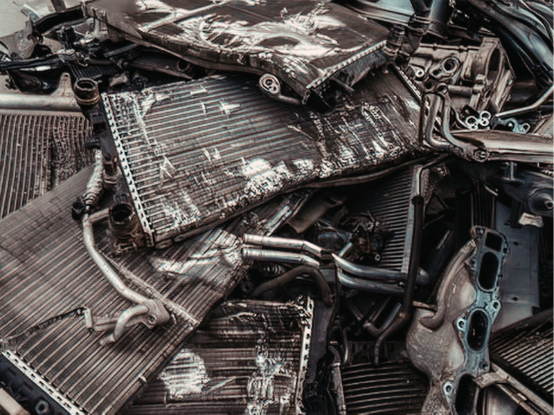 Damaged car radiator showing signs of pressure cycling fatigue and seam cracks